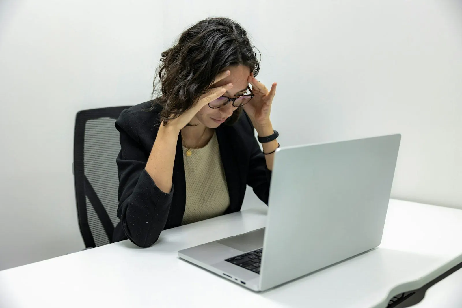 Une femme lassée, la main sur le front, devant son ordinateur au bureau